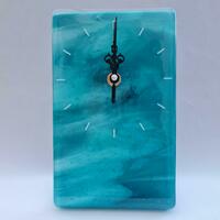 A blue and white streaked fused glass clock with black hands and white time markers