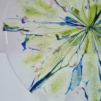 Detail of a large fused glass bowl with a watercolour design in green and blue with pink accents