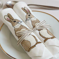 A set of two ivory cotton dinner napkins embroidered with a pair of rabbits by Kate Sproston Design