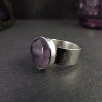 Large round purple amethyst gemstone on a wide hammered silver ring