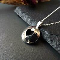 Hollow domed silver pendant with hammered texture, featuring a cut out heart