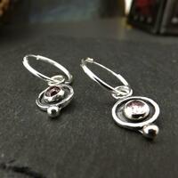 Small pink tourmaline gemstones set in silver circles and finished with a small silver ball, hung on sleeper hoop earrings
