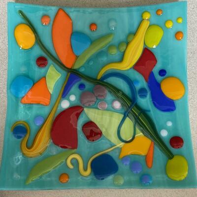 Abstract glass plate with turquoise background and bright yellow, orange and green shapes on it