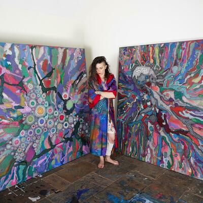 The Artist in her studio, beside two of her painting. 