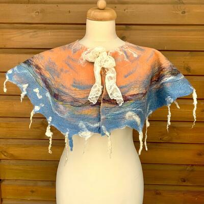 Felted cape on stand with coral and sky blue.