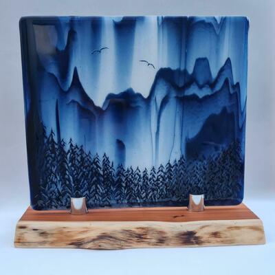 A fused glass panel in a blue and white china style on a Yew wood stand.