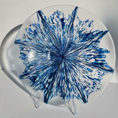 Large fused glass bowl in a range of blues formed to create a star pattern on a clear background.