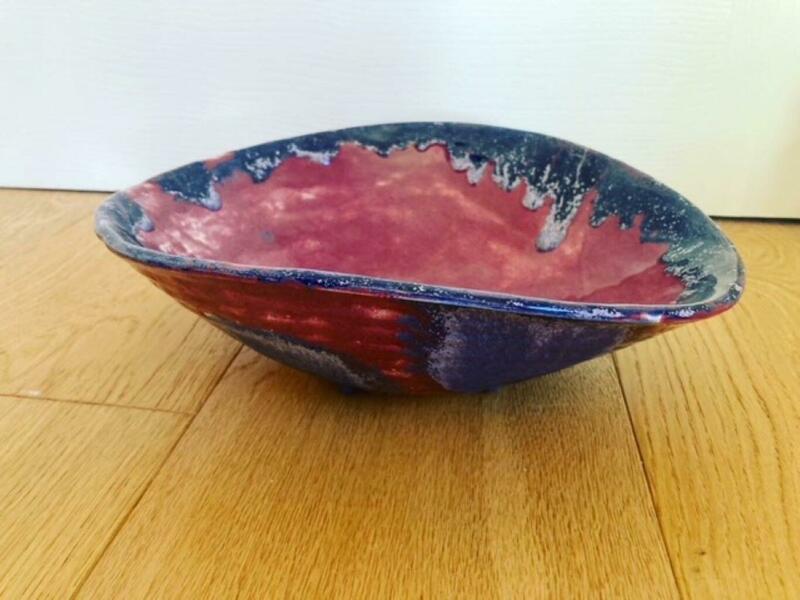 Red bowl with blue dripping glaze.