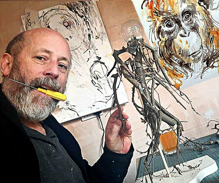 Working in my studio on a mixed media sculpture of running figure (twigs and light bulbs); in the background are 2 of my paintings of orangutans.