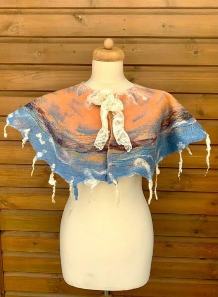 Felted cape on stand with coral and sky blue.