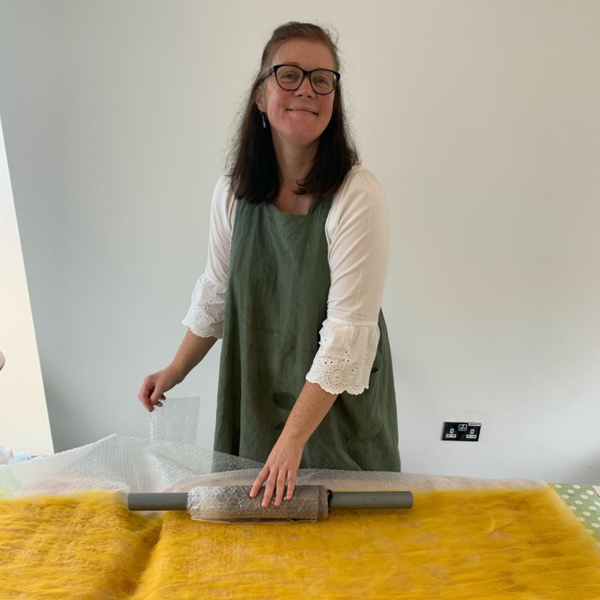 artist wearing apron smiling and felting