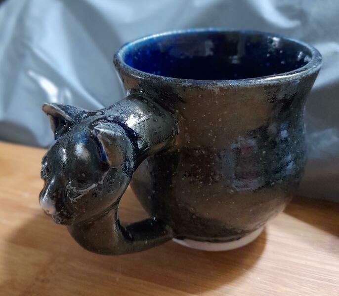 A stoneware black cat handled mug.  These designs were started with a lion.  They are 4 inches high and 4 inch diameter. Retail at £30 each. 