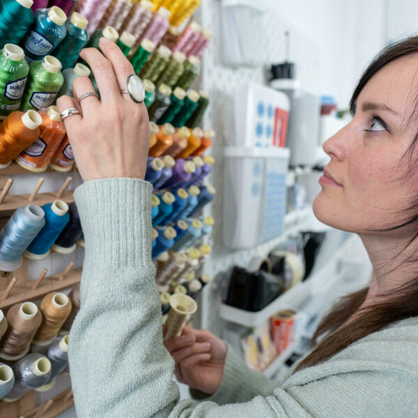 Kate Sproston working in her studio and choosing threads from a rack