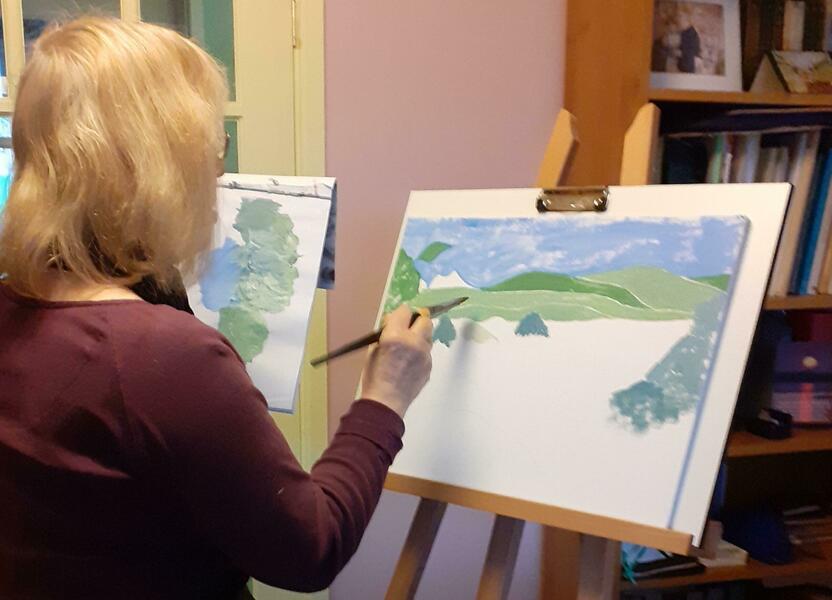 Sheila Robinson Acrylic Artist working on a new painting of hills and sky in blue and green