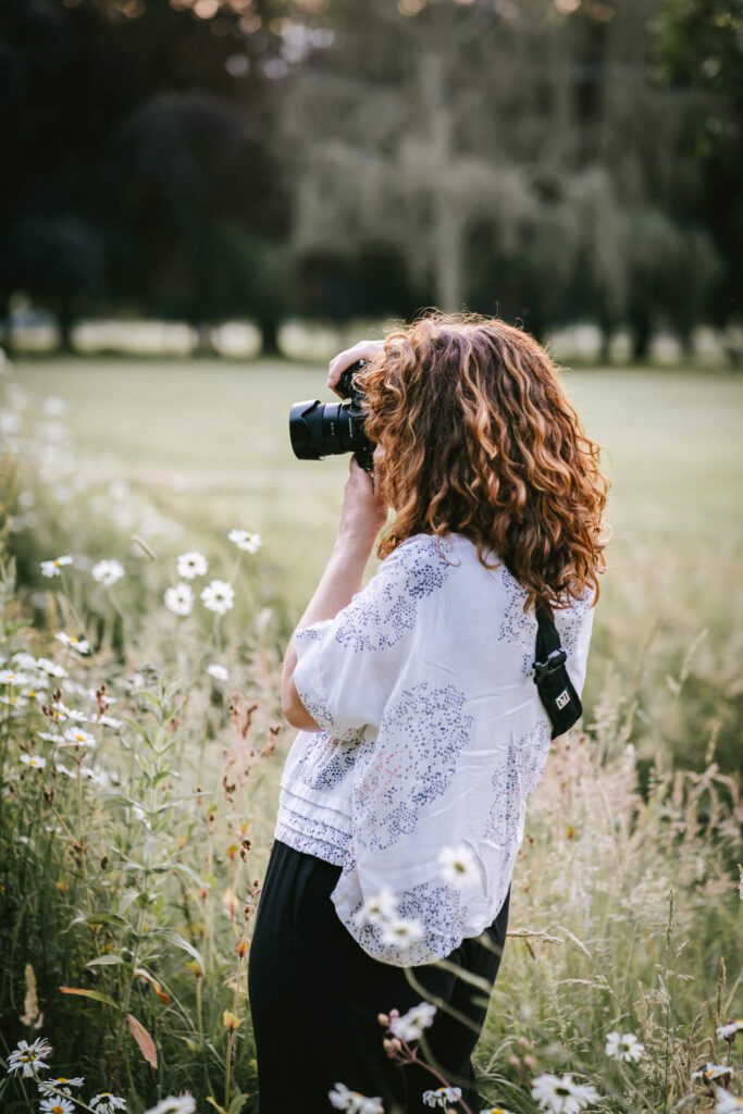 Natural light photographer and workshop leader photographing in a wildflower meadow, reflecting a relaxed, documentary style inspired by nature and real moments