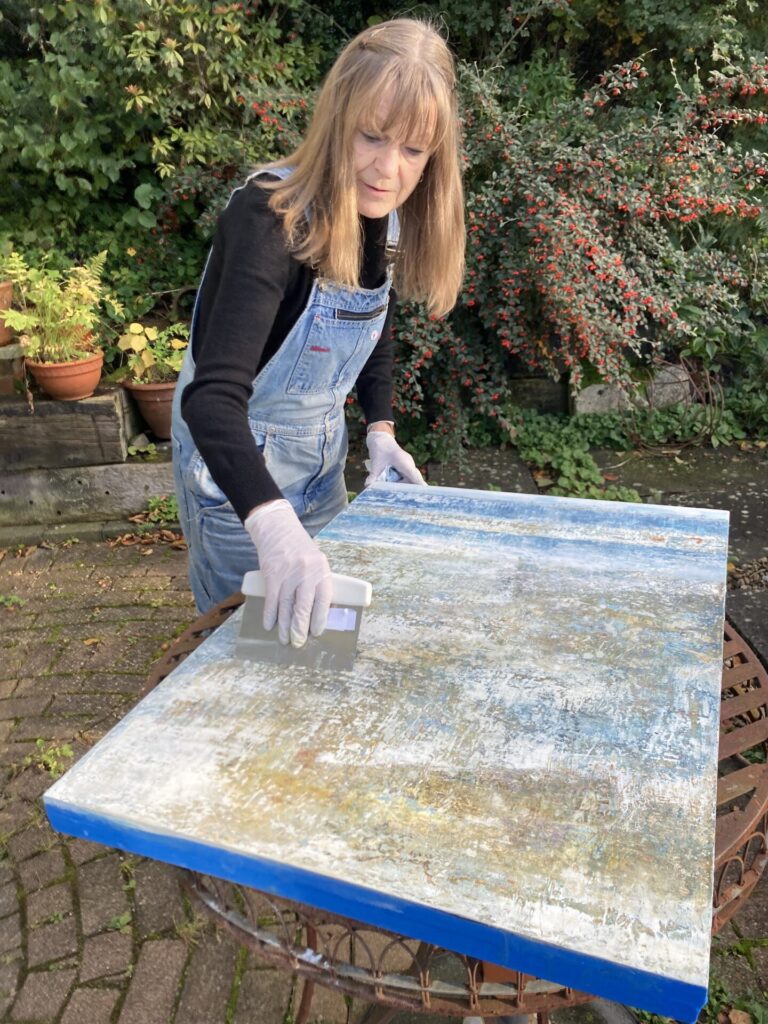 Scraping into the layers of oil and cold wax revealing the history beneath.