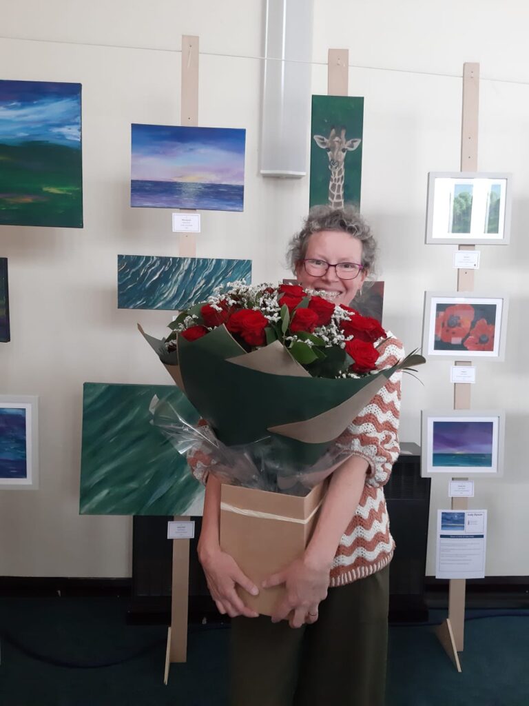 Judy standing in front of her paintings at Warwickshire Open Studios  2025