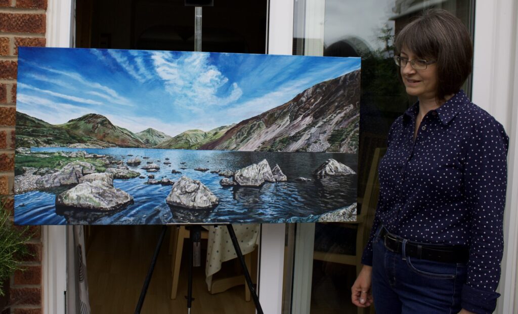 Image of artist standing next to an acrylic painting on canvas of Wastwater in the Lake District