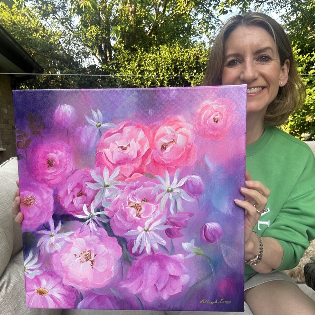 Nikki Lloyd-Evans holding painting of Magnolias and Camilla’s, called ‘Springtime Song’