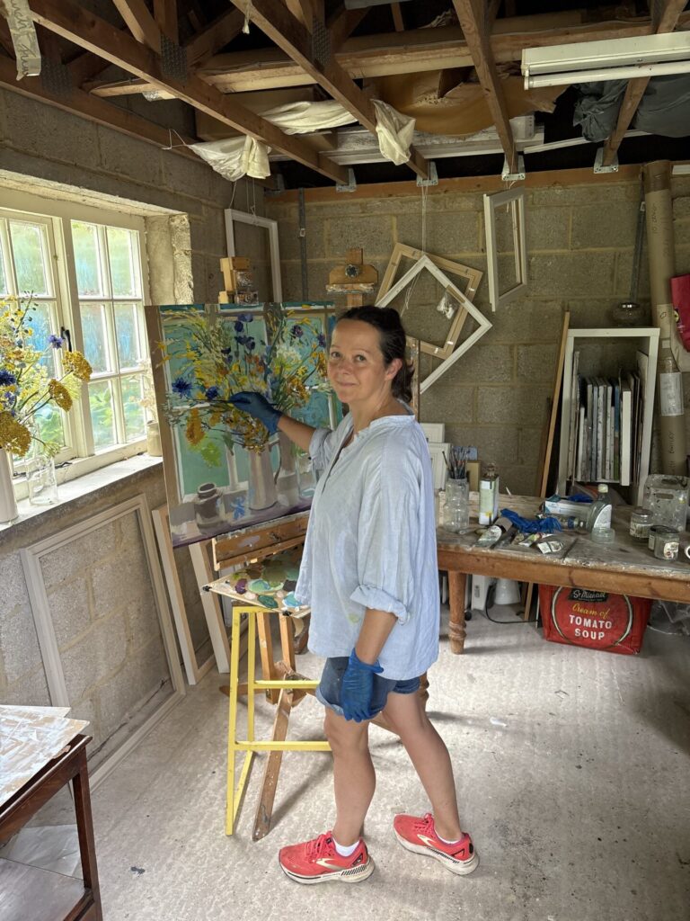Lizzie Bentley Painting her studio window garage flowers against window