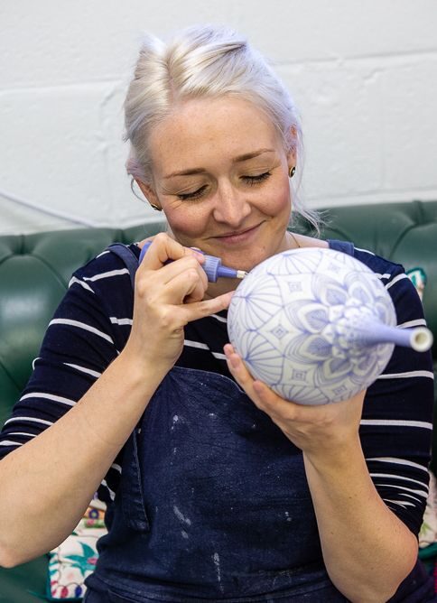 Rhian Malin hand painting a porcelain bottle in her studio